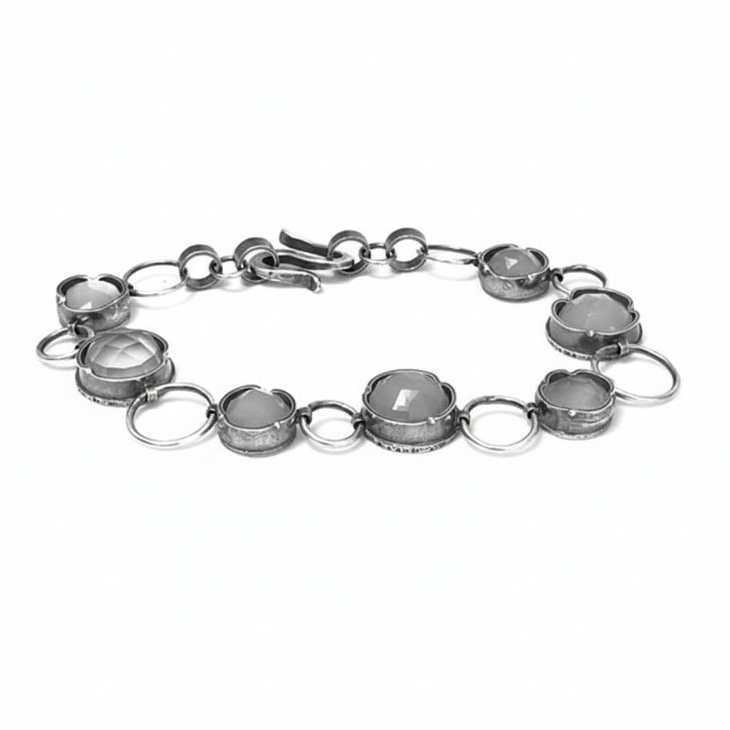 A silver bracelet featuring multiple gemstone settings with a chain link design.