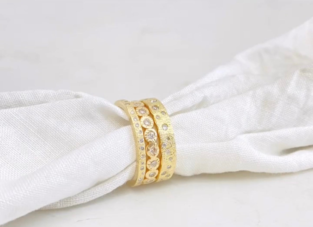 Gold ring with gemstones on a white fabric background
