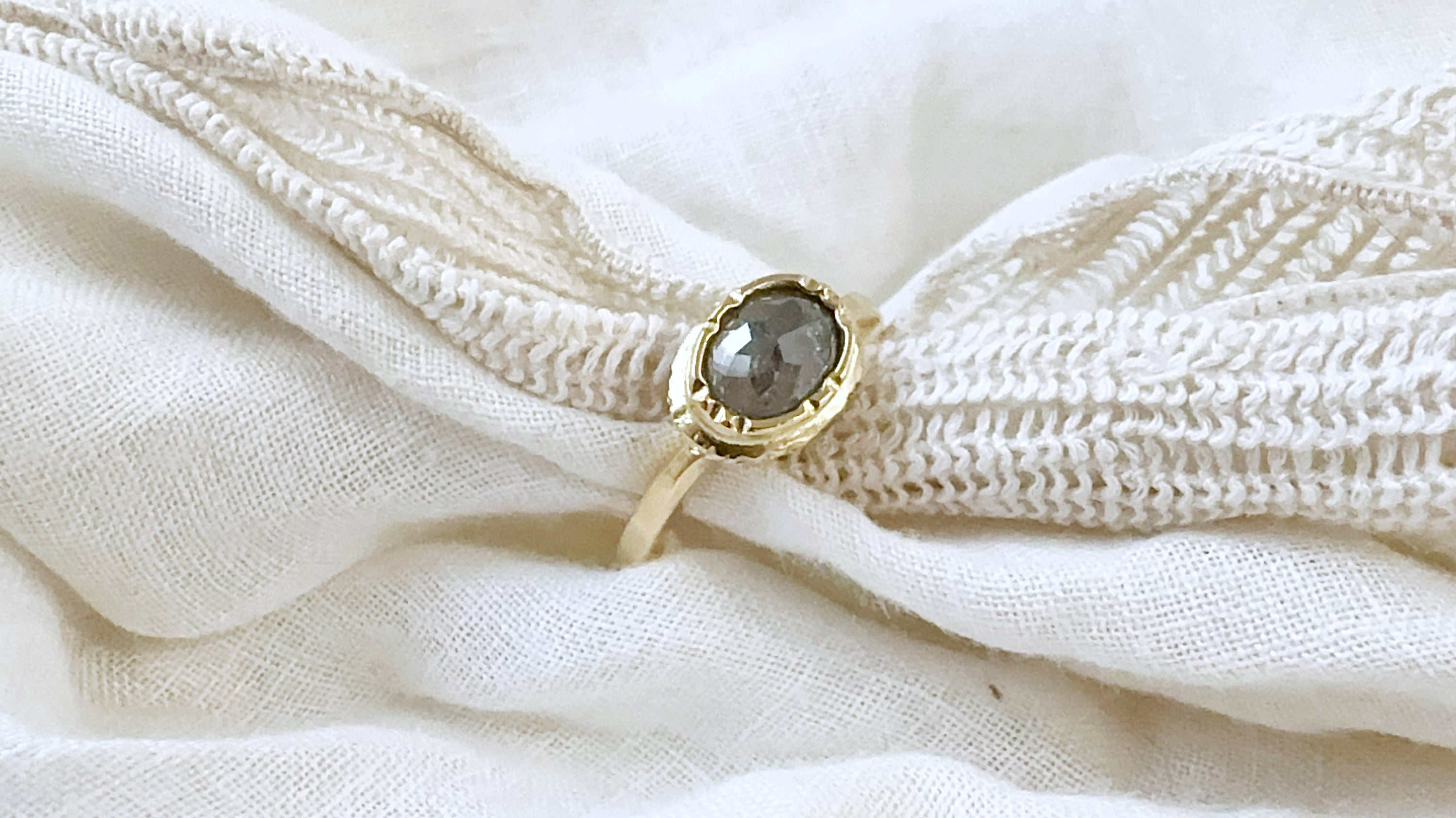 Gold ring with a gemstone on a textured white fabric background