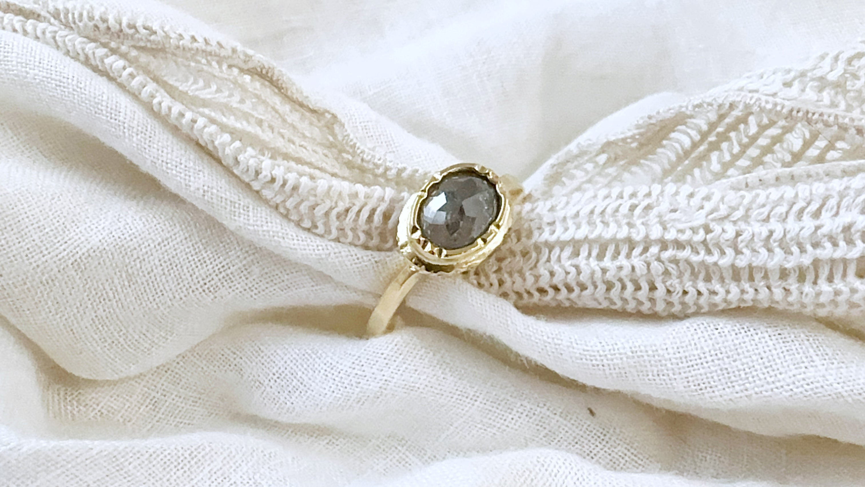 Gold ring with a gemstone on a textured white fabric background