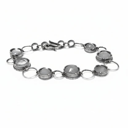 A silver bracelet featuring multiple gemstone settings with a chain link design.